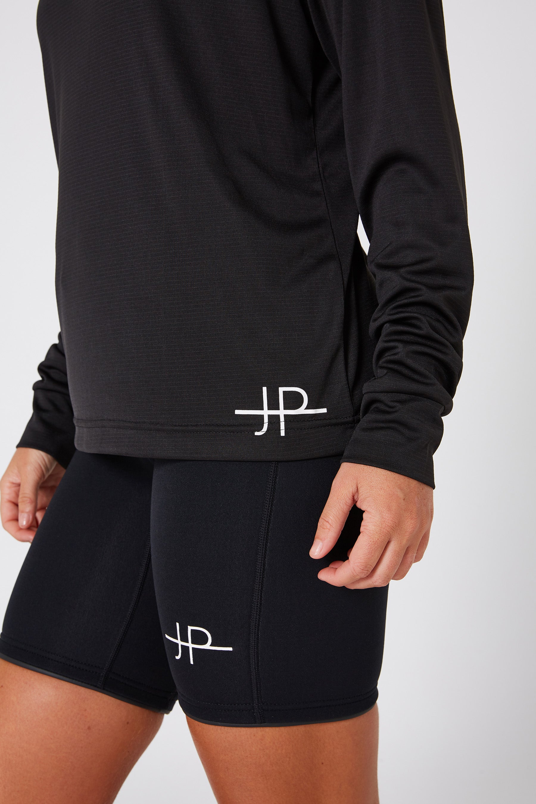 Black athletic outfit with a logo on shorts and jacket against a white background