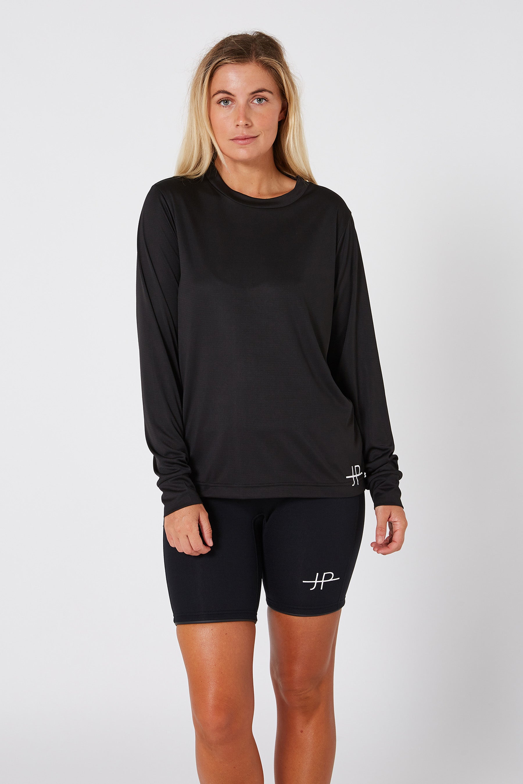 Woman wearing a black long-sleeve top and black shorts with a logo on a white background